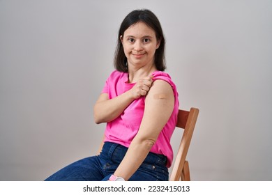 Woman with down syndrome wearing band aid for vaccine injection looking positive and happy standing and smiling with a confident smile showing teeth  - Shutterstock ID 2232415013