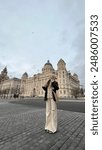 Woman in downtown Liverpool at the Royal Albert Dock. Cloudy daytime street photography. Beige neutral image and scenery.