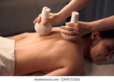 Woman dozing during hot compress massage performed by massotherapist - Powered by Shutterstock