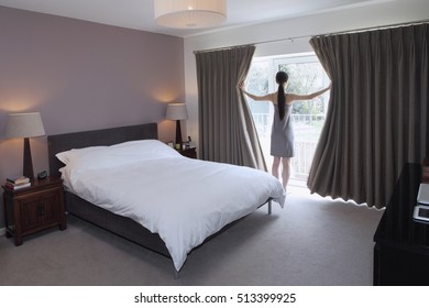 Woman drawing open curtains of bedroom - Powered by Shutterstock