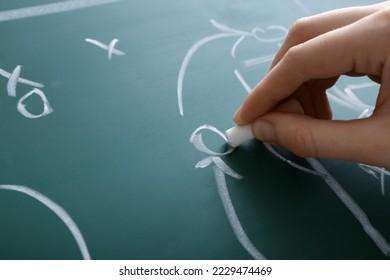 Woman drawing scheme of soccer game on green chalkboard, closeup