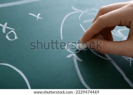 Woman drawing scheme of soccer game on green chalkboard, closeup
