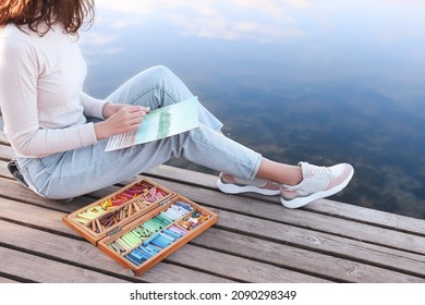 Woman drawing and soft pastels wooden pier near river  closeup