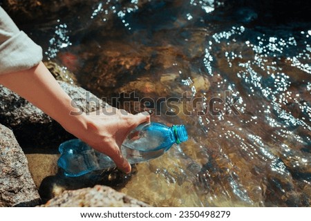 Woman draws clean spring water into a plastic bottle