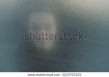 Woman dreamy or mystery portrait through the glass. Psychological concept of concentrating