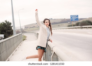 woman in the dress dabbles in sidewalk along the road bridge, there is a transport along the road - Shutterstock ID 1281411550