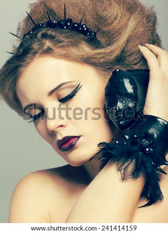 Woman in dress and diadem made of molten vinyl disk with alien face in hands