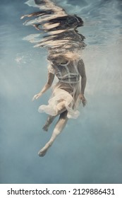    A Woman In A Dress Swims Underwater As If Floating In Zero Gravity                            