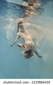    A Woman In A Dress Swims Underwater As If Floating In Zero Gravity                            