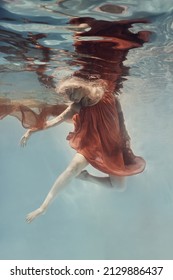    A Woman In A Dress Swims Underwater As If Floating In Zero Gravity                            