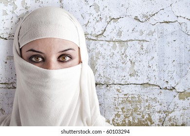 woman dressed in Arab costume, rusty wall in the background