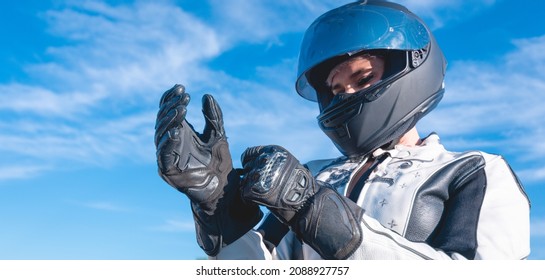 Woman Dressed As A Biker With Black Safety Helmet Putting On Her Leather Gloves Getting Ready To Ride A Motorcycle