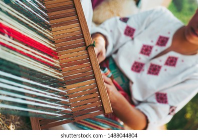 Woman Dressed In Colorful Traditional Native Serbian Closing Knitting A Carpet With National Pattern