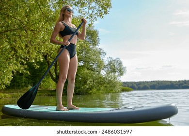 Woman, dressed in a fashionable swimsuit, engages in a dynamic sup board activity, active lifestyle 