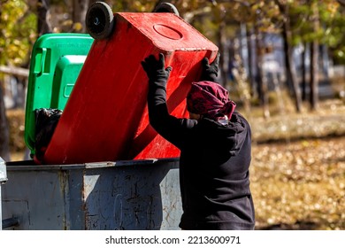 A Woman Dressed As A Garbage Collector Overturns A Park Cleaning Container