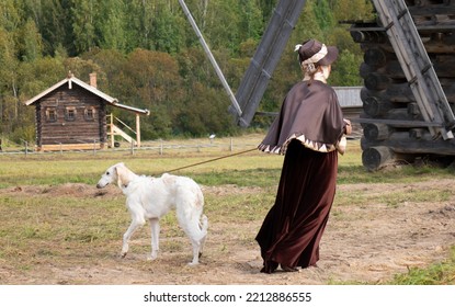 A Woman Dressed In A Historical Costume, With An Afghan Greyhound. The Dog And The Owner Are Walking In The Autumn Park.