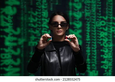 Woman dressed in matrix style with blue and red pills on dark background. Concept of choice