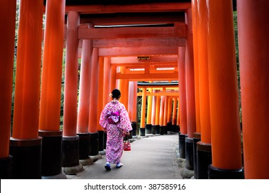 Woman Dressed In Traditional Japanese Costume Walking Under Tori Gates At The Fushimi-inari Shrine, Kyoto Japan