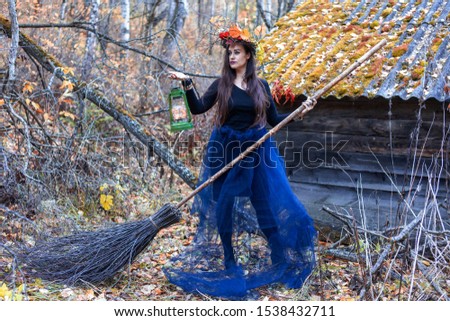 Woman dressed as a witch in the autumn forest near the old house