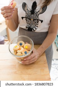 Woman Dressed In Zebra T-shirt Picking A Red Top Cookie With Her Right Hand And Showing An Opened Jar Full Of Colorful Cookies.