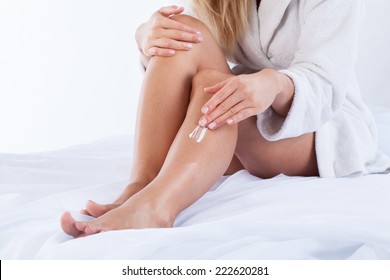 Woman In Dressing Gown Using Body Cream