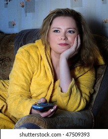 Woman In Dressing Gown Watches TV Sitting On Sofa