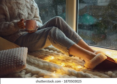 Woman with drink sitting on soft plaid near window in evening, closeup - Powered by Shutterstock