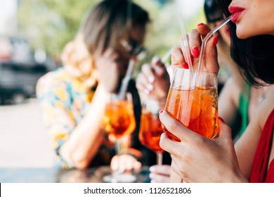 Woman Drinking Aperol Spritz, With Friends At Dinner Table