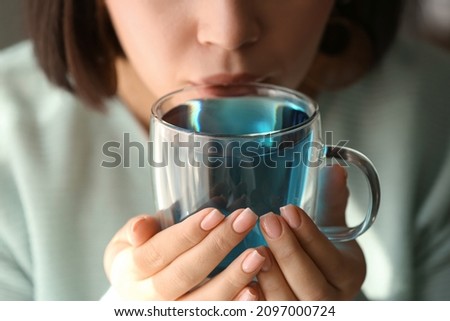 Woman drinking butterfly pea flower tea, closeup