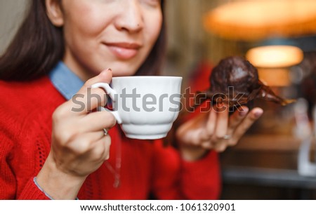 woman drinking coffee and eating a delicious muffin cake in modern city cafe