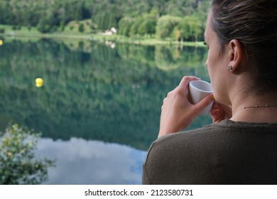 Woman Drinking Coffee In Front Of The Lake Of Her Rural Accommodation