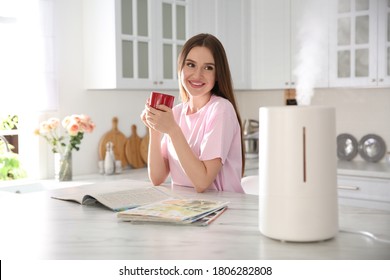 Woman drinking coffee in kitchen with modern air humidifier