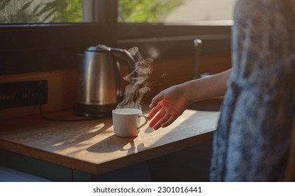 Woman is drinking coffee , morning routine. Tiny house. First property. Small apartment interior design. Minimalism. Moving in. Living alone. Charming trailer house with the morning sun - Powered by Shutterstock