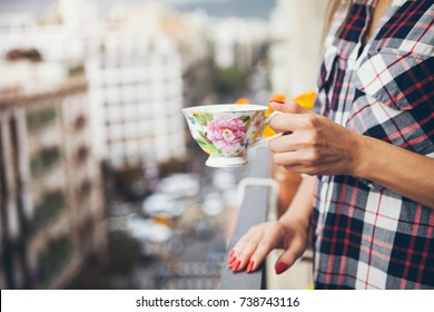 Woman Is Drinking Coffee On A Balcony With Big City View. Close Up Of Hands With  Cup Of Coffee. Early Morning Routine