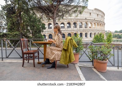 Woman Drinking Coffee At Outdoor Cafe Near Coliseum, The Most Famous Landmark In Rome. Concept Of Italian Lifestyle And Traveling Italy. Street View