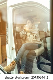 Woman Drinking Coffee Sitting In The Front Seat Of A Camper Van