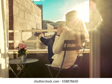 Woman drinking coffee under sun, outdoor on balcony with city view