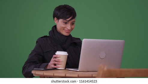 Woman Drinking Coffee Using Laptop Computer At A Cafe Table On Green Screen