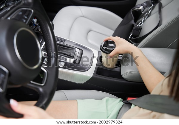 Woman drinking coffee while driving a car\
during the road to the\
workplace