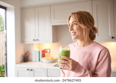 Woman Drinking Fresh Healthy Homemade Smoothie From Glass In Kitchen At Home - Powered by Shutterstock