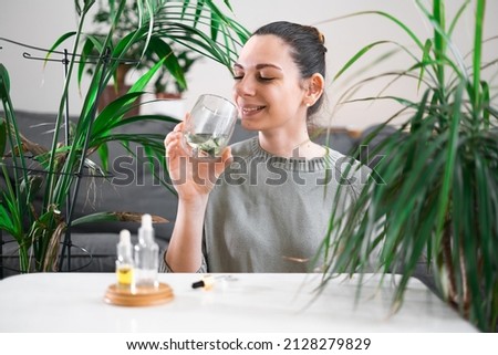 Woman drinking glass with Chlorophyll water, antioxidant beverage. Healthy lifestyle 