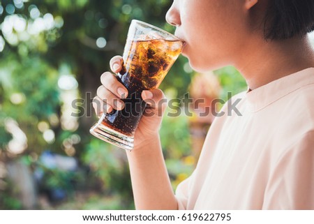 Woman drinking a glass of cola with ice.