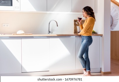 Woman Drinking A Glass Of Wine In A Modern Kitchen