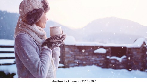 Woman drinking Hot Tea or Coffee from Festive Cup with Snowy Mountain View on Background. Beautiful Girl Enjoying Winter Morning or Evening Outdoors under the snowfall. Christmas Holidays - Powered by Shutterstock