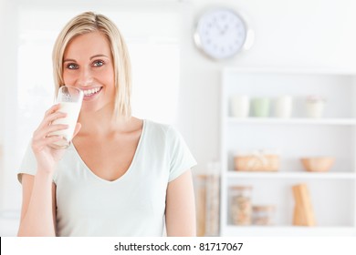 Woman Drinking Milk Looks Into Camera In Kitchen