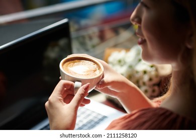 Woman drinking morning coffee and working working on computer in coffeeshop