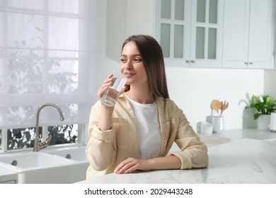 Woman Drinking Tap Water From Glass In Kitchen