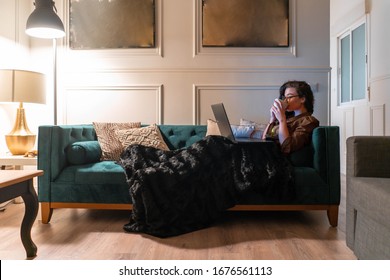 Woman Drinking Tea And Watching Movies Or TV Series At Home. Communicating With Friends And Colleagues from Home And Living In Quarantine. Coronavirus. Image contains noise, grains
