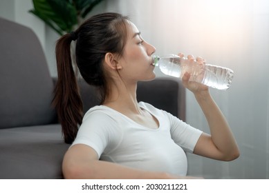 woman drinking water after exercise to fill dehydration - Shutterstock ID 2030211221