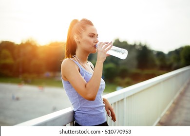 Woman drinking water after running to stay hydrated